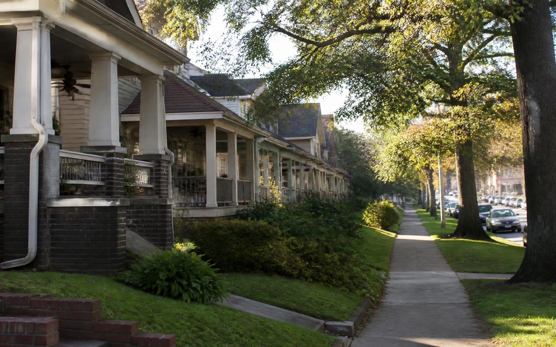 Row of craftsman bungalows with deep front porches along a shaded sidewalk in Dilworth, Charlotte