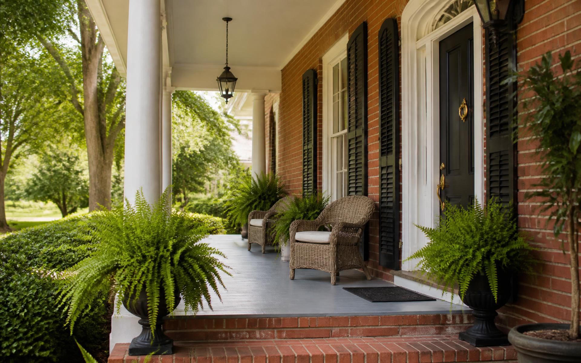 Covered brick front porch with white columns on a 1920s Myers Park home