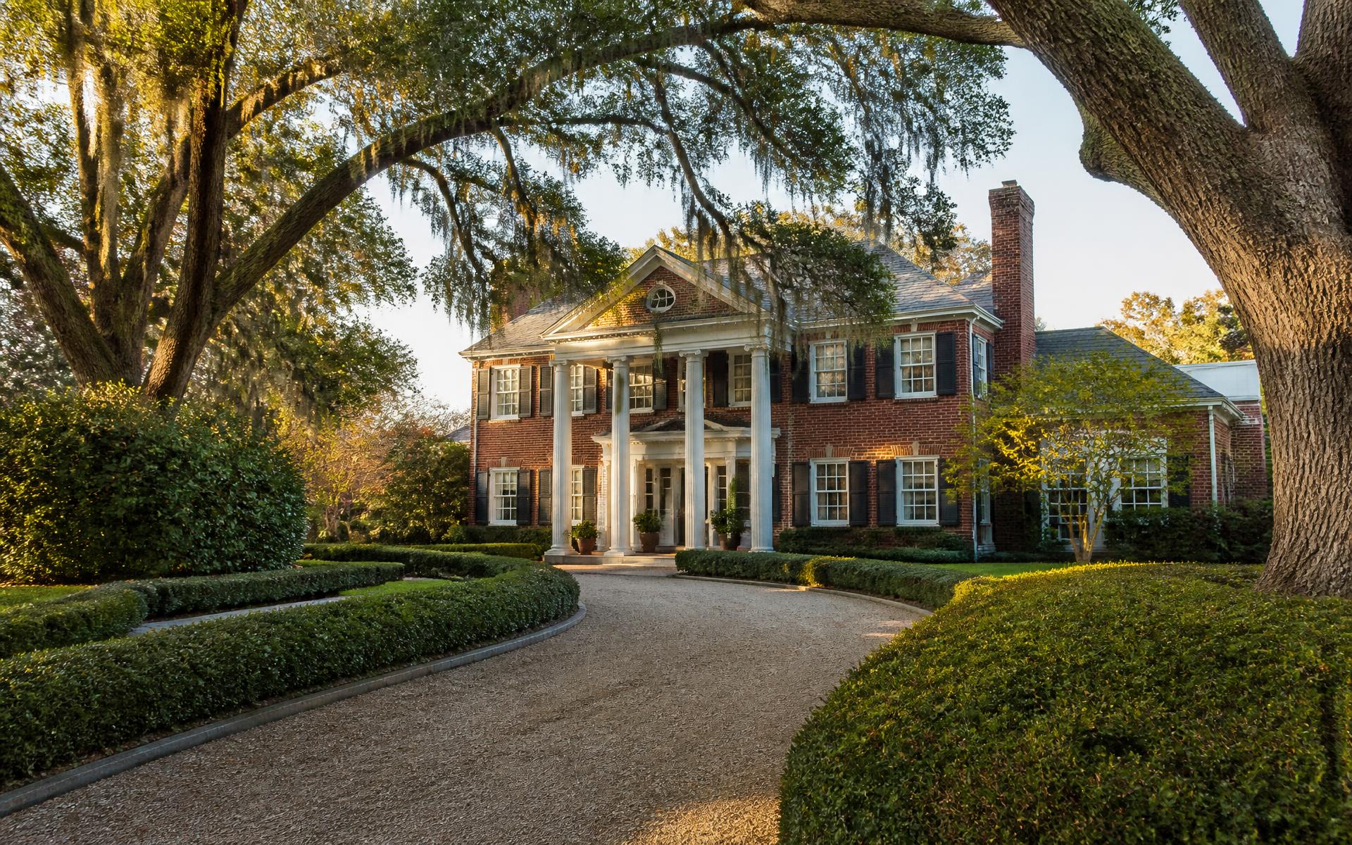 Brick Colonial Revival home behind a curving gravel drive and clipped boxwood hedges in Myers Park, Charlotte