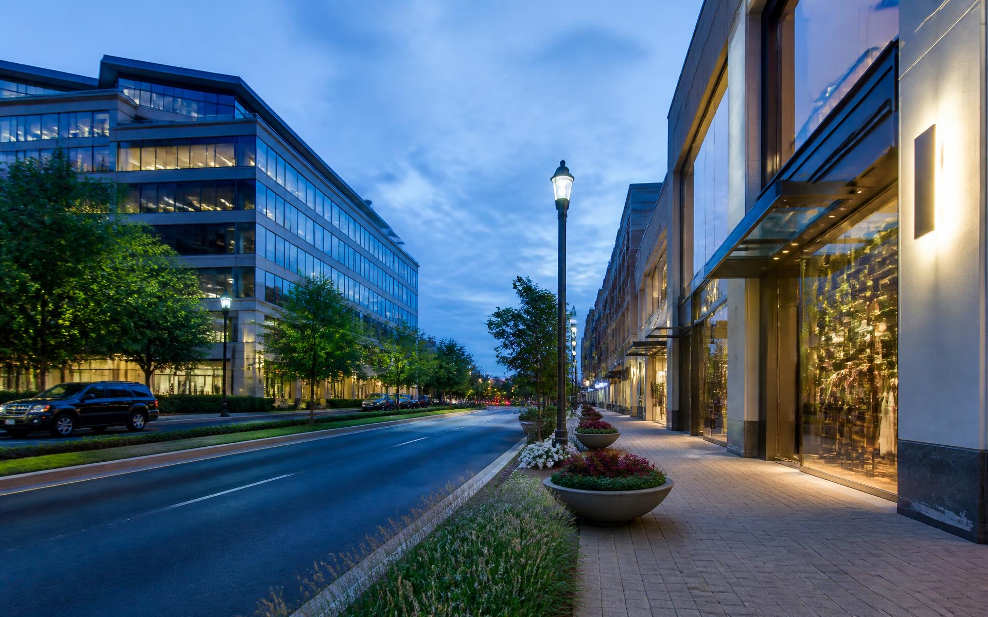 Landscaped boulevard lined with mid-rise offices and luxury shopfronts at blue hour in SouthPark, Charlotte